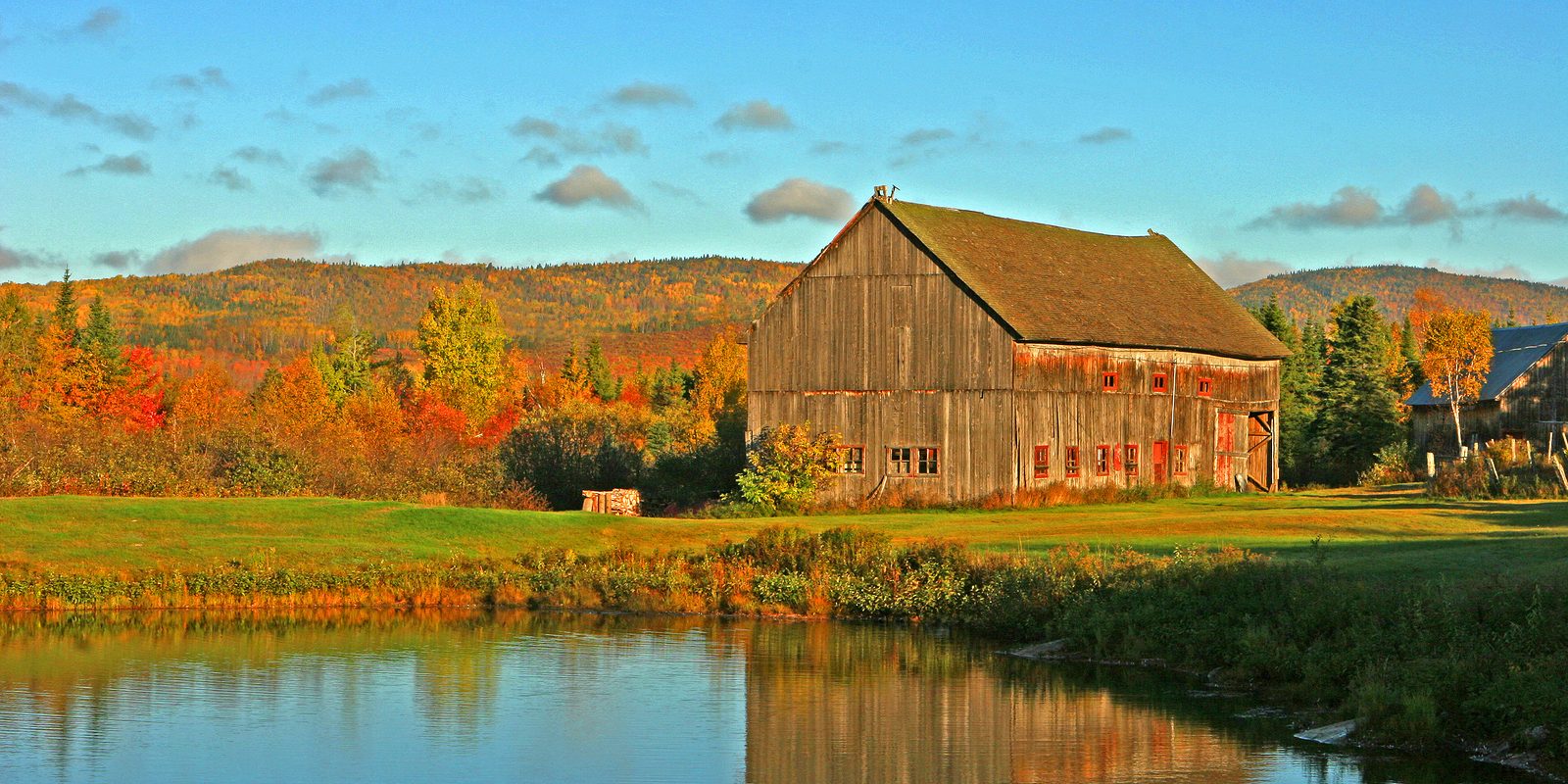 an old barn,in the fall, reflects in the pond in the morning light, repurposed barn materials