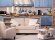 Close up view on kitchen studio. Living room with small sofa, chair and coffe table with kitchen on background.